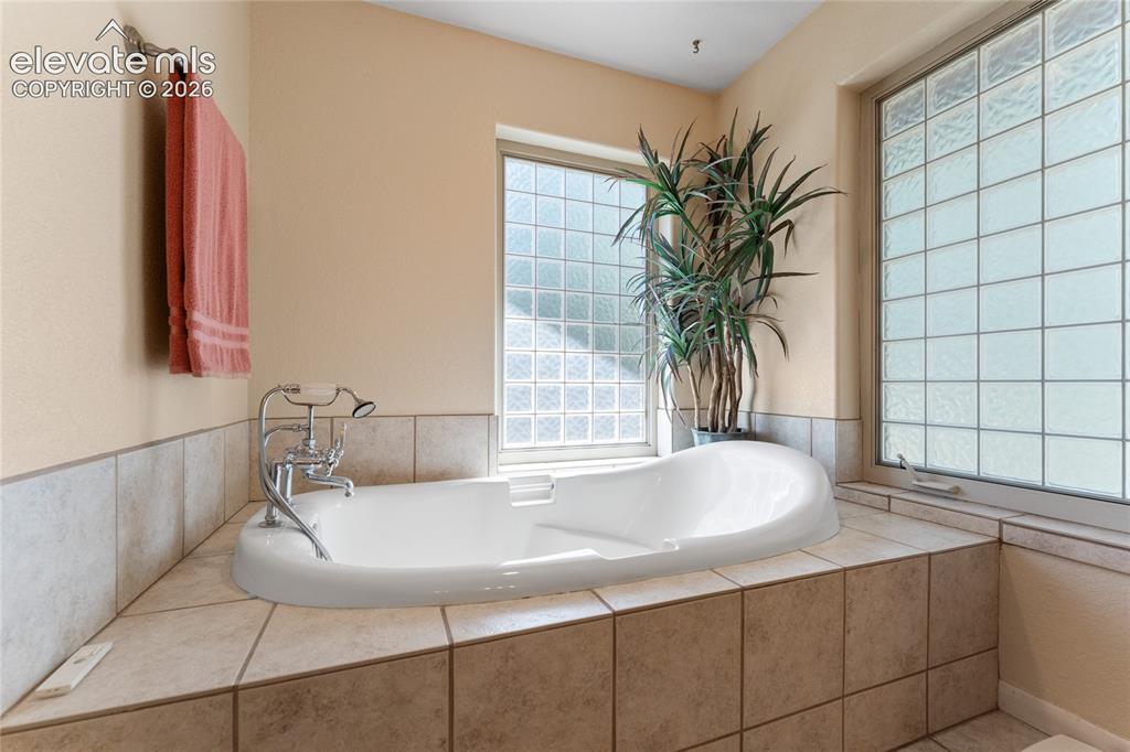 657 Spring Valley Drive Divide, CO 80814 - Photo 12 of 43 Soaking tub set within a tiled surround, featuring a chrome faucet with a handheld sprayer