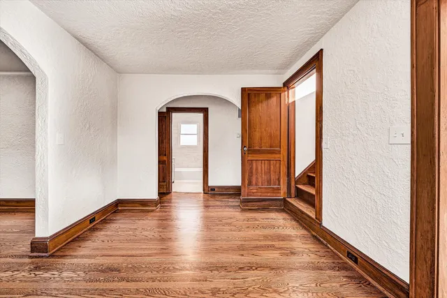 a view of empty room with wooden floor and fan
