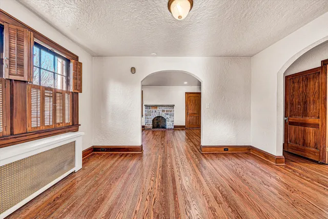a view of empty room with wooden floor and fireplace