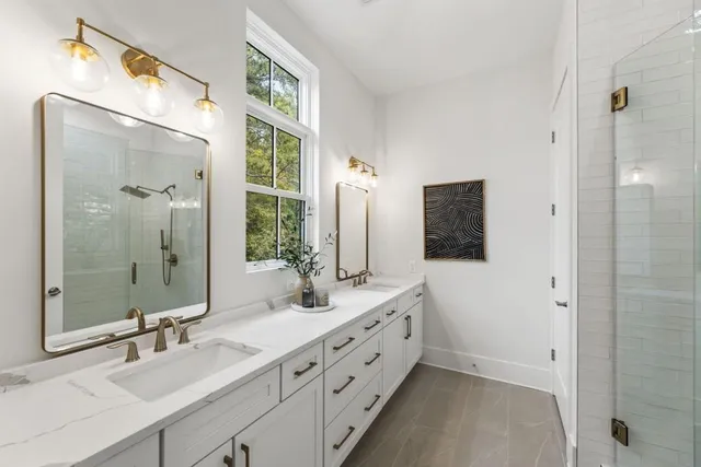 a bathroom with a double vanity sink mirror and shower