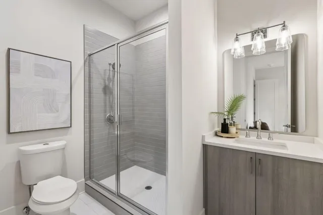a bathroom with a shower sink vanity mirror and toilet
