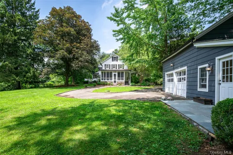 a view of a house with a big yard potted plants and large tree
