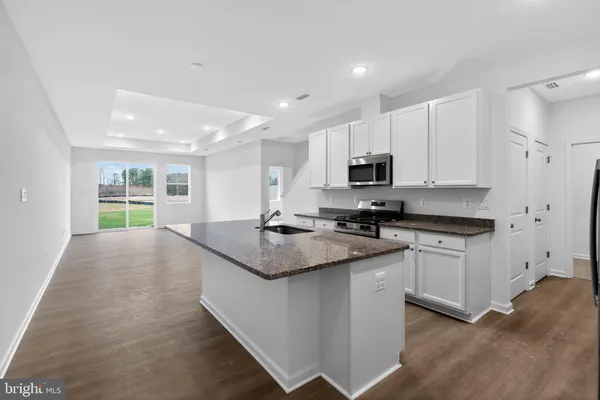 a kitchen with granite countertop a sink stove and refrigerator