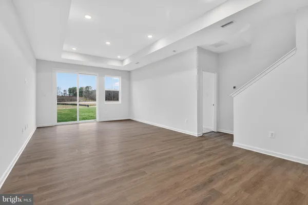 a view of an empty room with wooden floor and windows