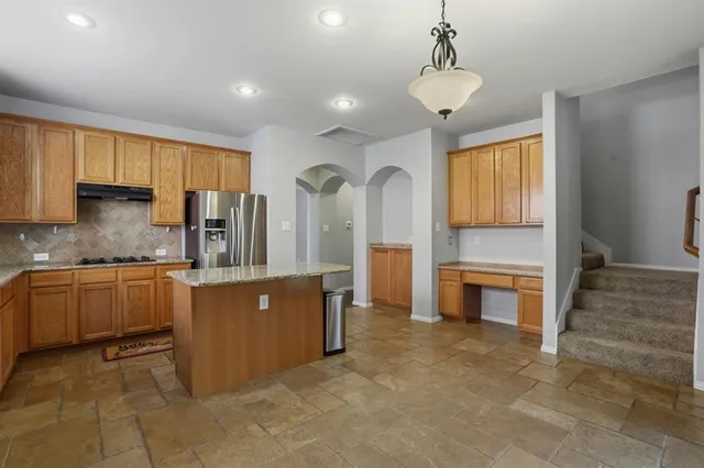 a kitchen with stainless steel appliances granite countertop a refrigerator a sink dishwasher stove and oven