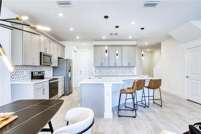 a kitchen with kitchen island a dining table chairs stainless steel appliances and cabinets