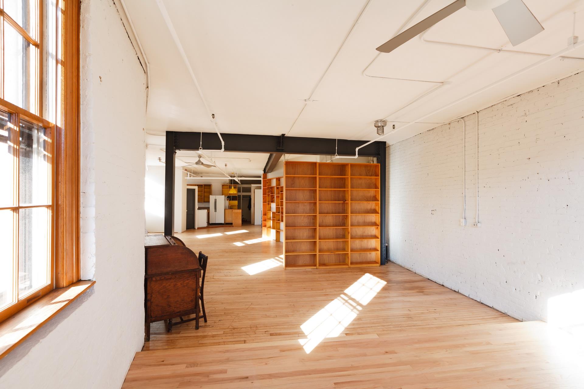 210 Spring Street, Unit 5 Manhattan, NY 10012 - Photo 9 of 13 an empty room with wooden floor and windows