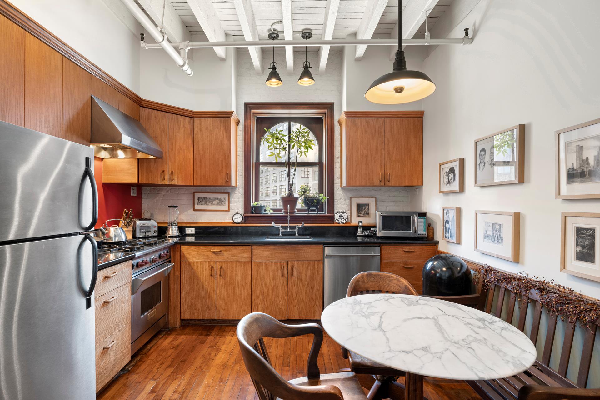 210 Spring Street, Unit 5 Manhattan, NY 10012 - Photo 2 of 13 a kitchen with stainless steel appliances a dining table chairs refrigerator and sink