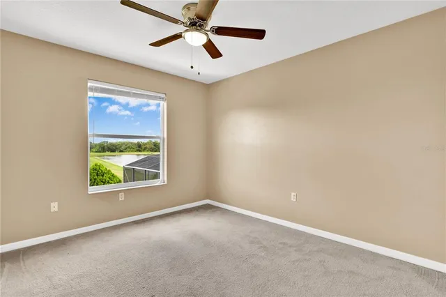 an empty room with windows and ceiling fan