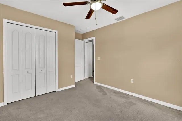an empty room with a ceiling fan and window