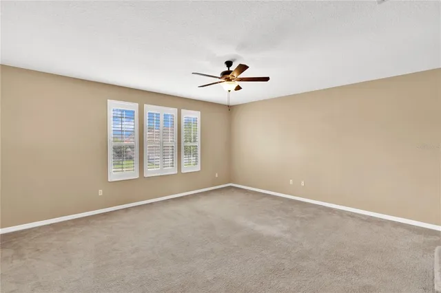 an empty room with windows and chandelier fan