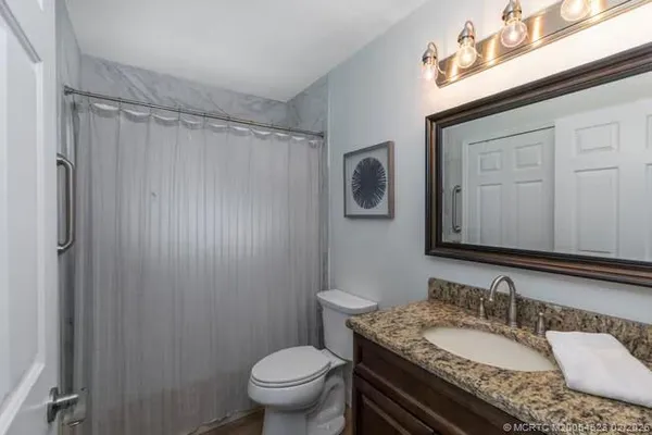 a bathroom with a granite countertop sink toilet and shower