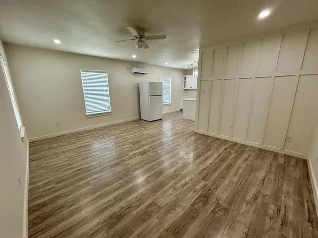 an empty room with wooden floor and windows
