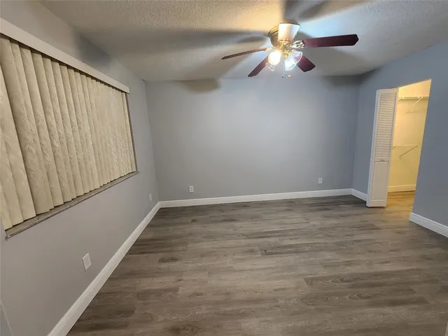 a view of an empty room with chandelier fan and wooden floor