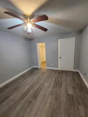 an empty room with wooden floor chandelier fan and windows
