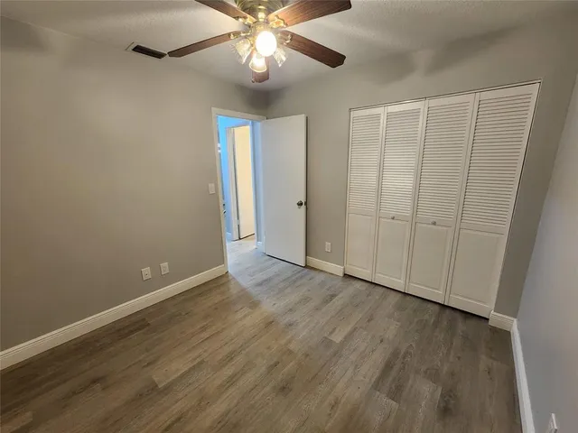 an empty room with wooden floor chandelier fan and closet area