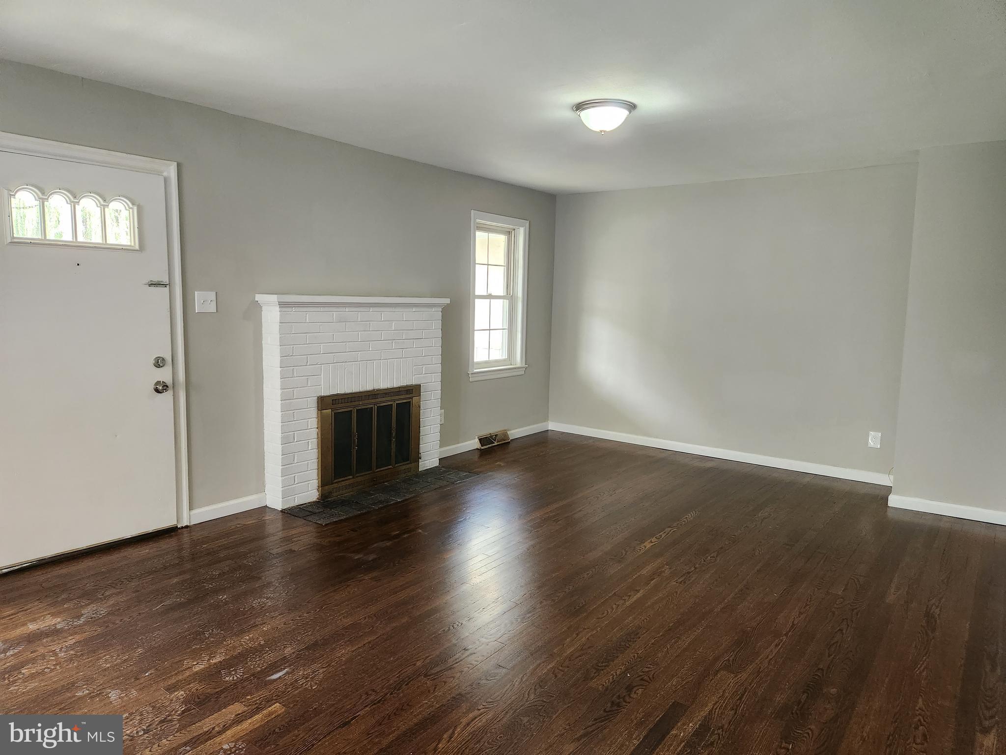 10 Webster Avenue Stratford, NJ 08084 - Photo 3 of 20 an empty room with wooden floor fireplace and windows