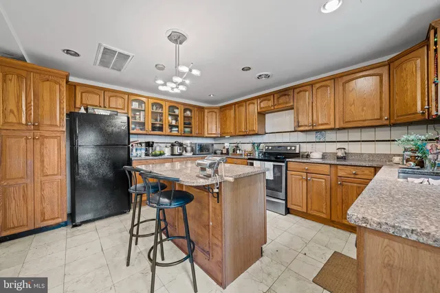 a kitchen with stainless steel appliances granite countertop a refrigerator a sink dishwasher a stove with wooden cabinets and floor