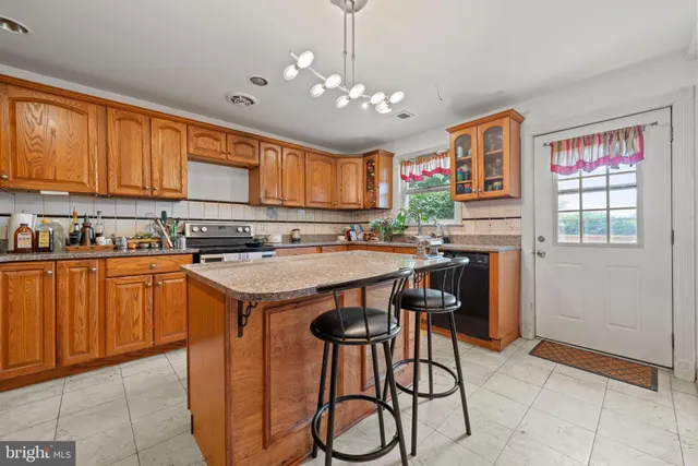 a kitchen with stainless steel appliances granite countertop a stove top oven a sink dishwasher and a refrigerator with wooden cabinets