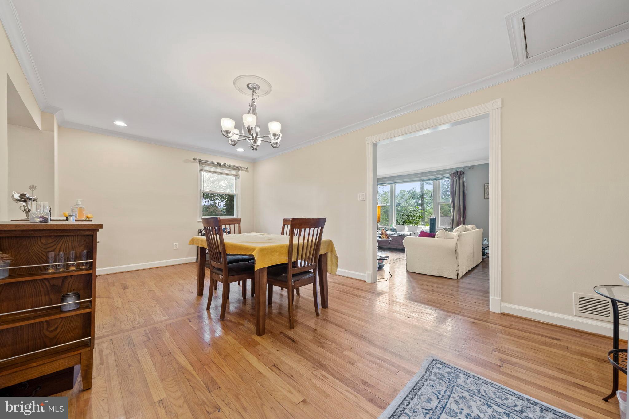 6517 29th Street North Arlington, VA 22213 - Photo 9 of 49 a dining room with wooden floor a chandelier a glass table and chairs