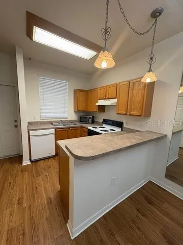 an empty room with a chandelier fan and windows