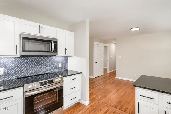 a kitchen with granite countertop white cabinets and white appliances