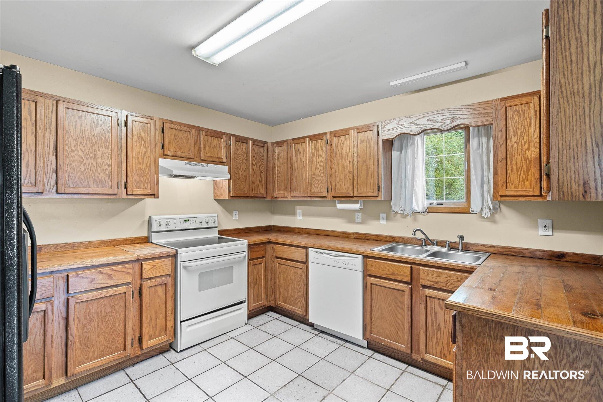 13908 White Road Silverhill, AL 36576 - Photo 6 of 23 Kitchen featuring white appliances, light tile patterned floors, brown cabinets, and under cabinet range hood