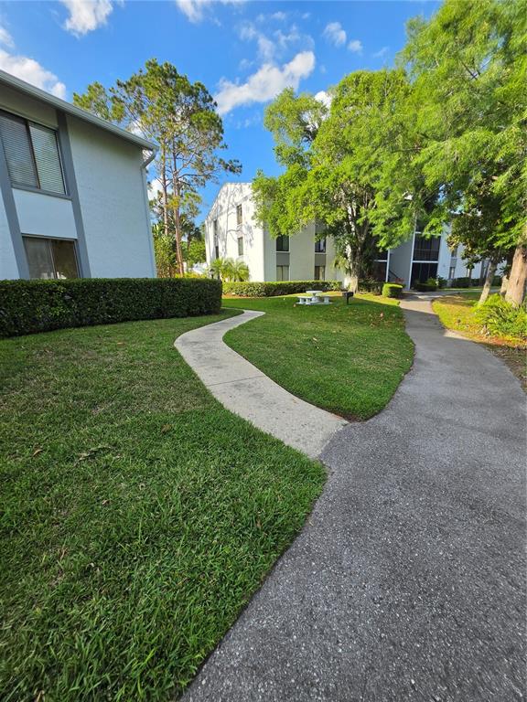 1281 Pine Ridge Circle East, Unit B1 Tarpon Springs, FL 34688 - Photo 2 of 30 a view of a house with a big yard potted plants and large tree