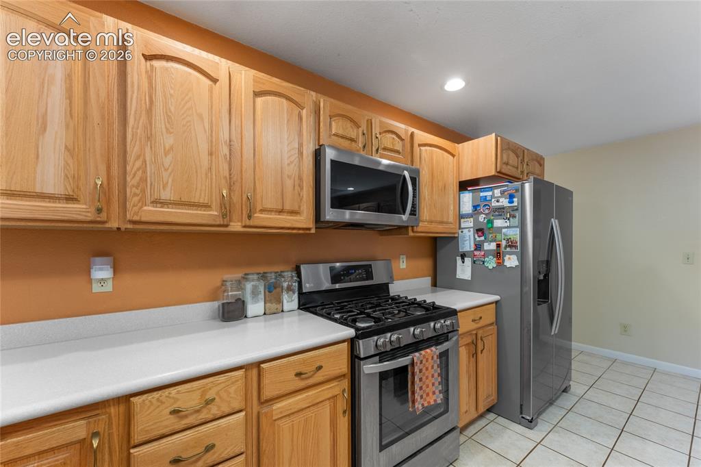 657 Spring Valley Drive Divide, CO 80814 - Photo 18 of 43 Kitchen featuring light wood cabinetry, stainless steel appliances, white countertops, and tiled flooring