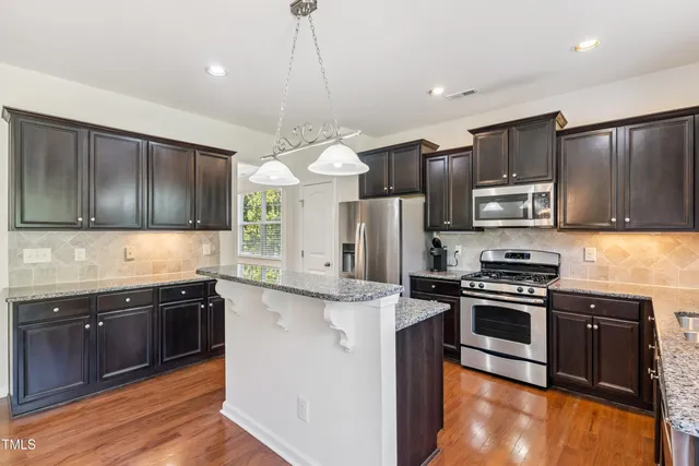 a kitchen with stainless steel appliances granite countertop a sink stove and refrigerator