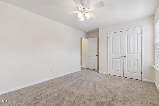 an empty room with a ceiling fan and a window