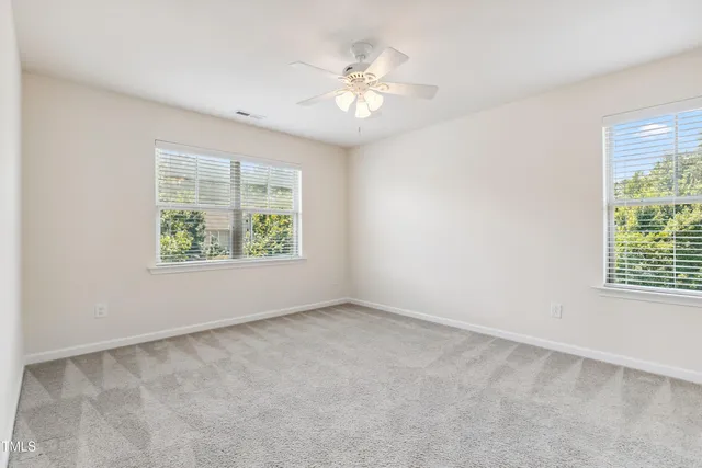 an empty room with windows and chandelier fan