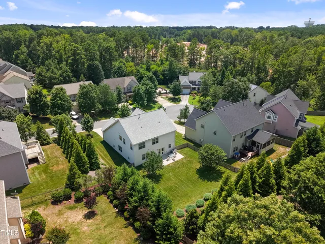 an aerial view of residential house with outdoor space and trees all around