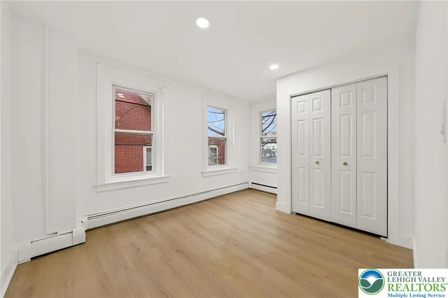 a view of an empty room with wooden floor and closet