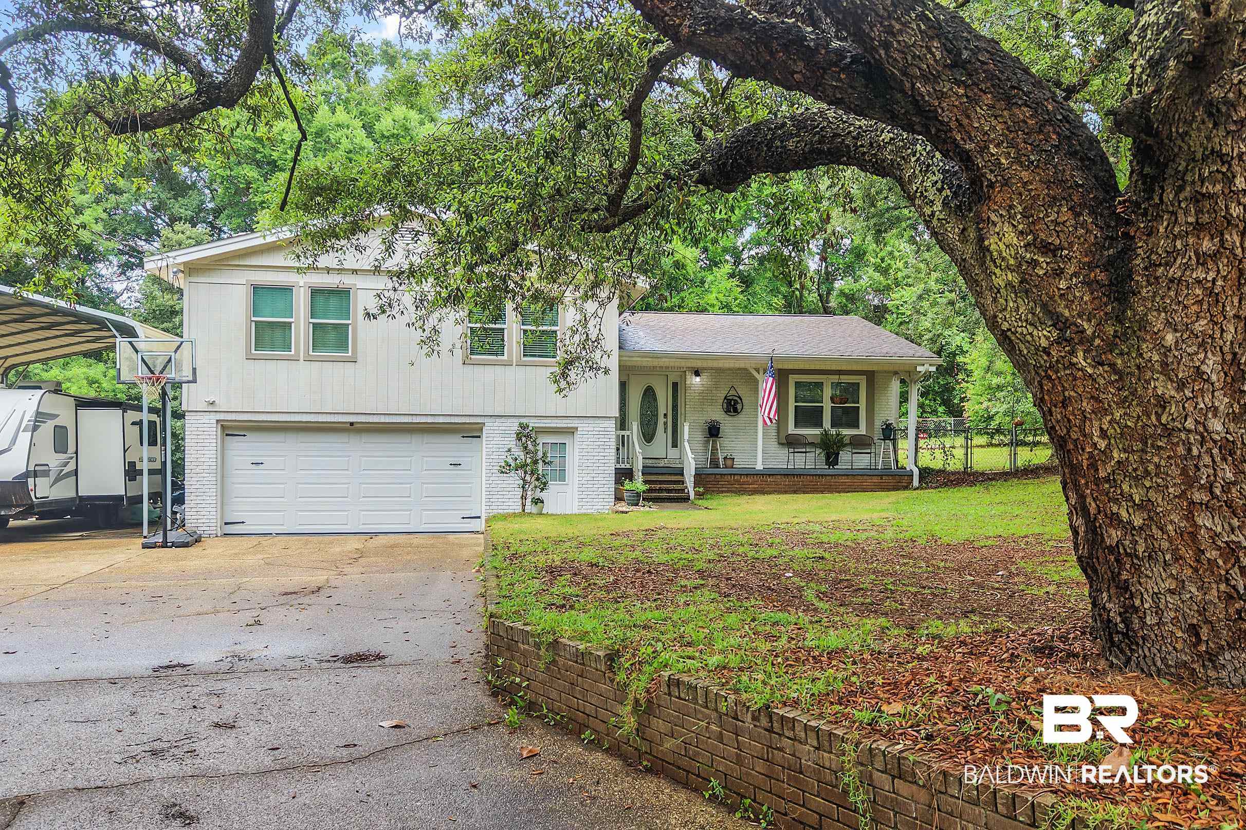 33129 Antietam Road Lillian, AL 36549 - Photo 2 of 31 Split-level residence featuring a two-car garage, front porch, and mature trees