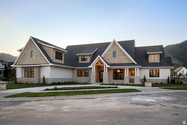 View of front of house featuring stone siding, board and batten siding, a shingled roof, and a porch
