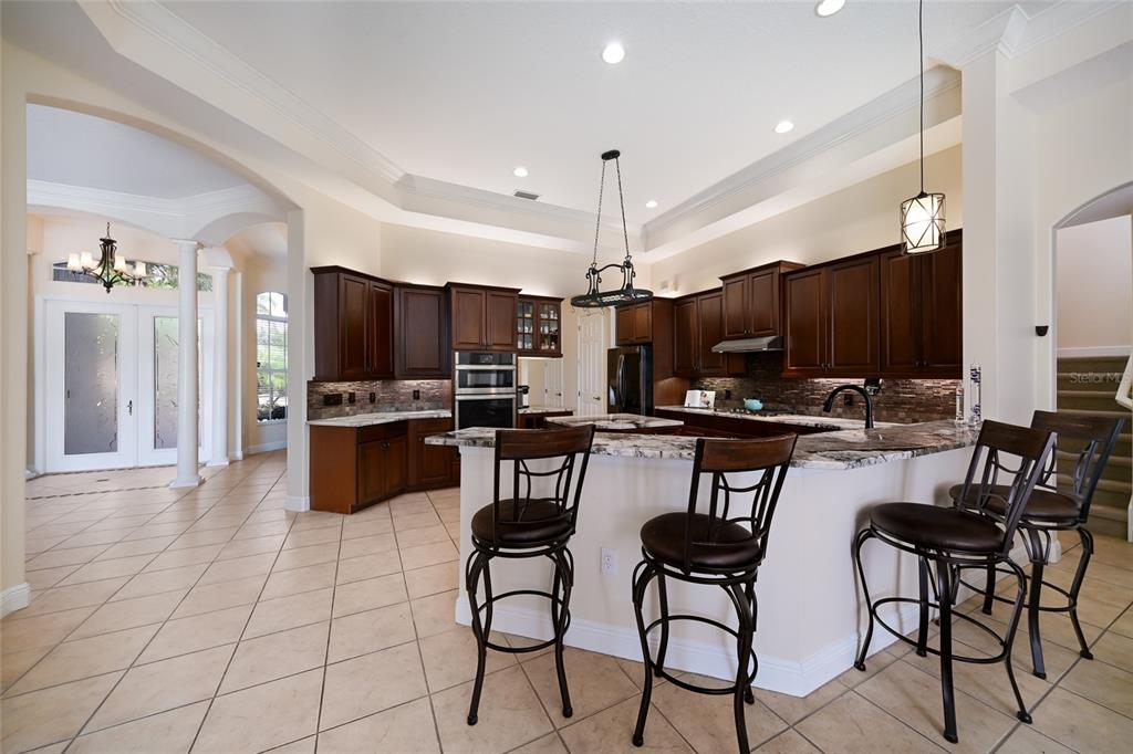 14806 Bowfin Terrace Lakewood Ranch, FL 34202 - Photo 18 of 58 a kitchen with stainless steel appliances kitchen island granite countertop a stove a sink a microwave a dining table and chairs