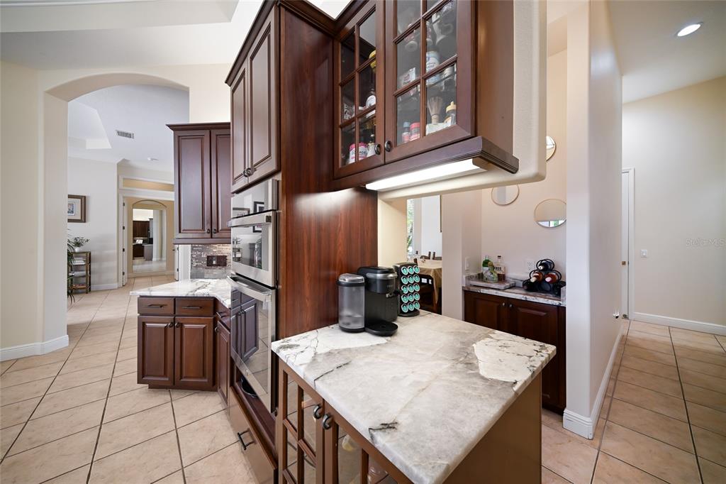 14806 Bowfin Terrace Lakewood Ranch, FL 34202 - Photo 19 of 58 a kitchen with stainless steel appliances kitchen island granite countertop a refrigerator a stove and a sink with wooden cabinets