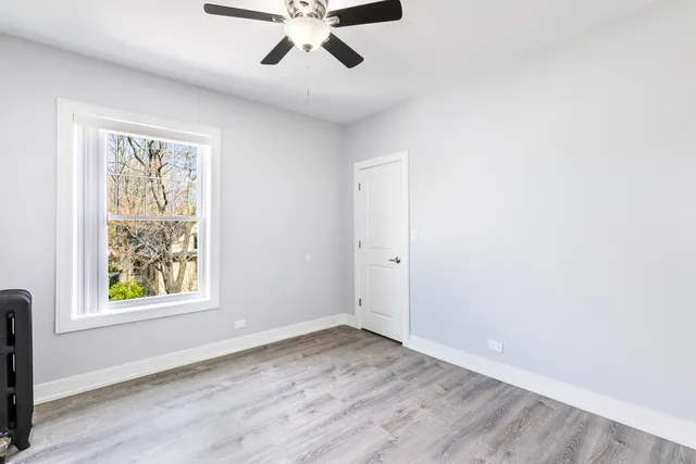 an empty room with wooden floor fan and windows