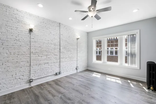 an empty room with windows and ceiling fan