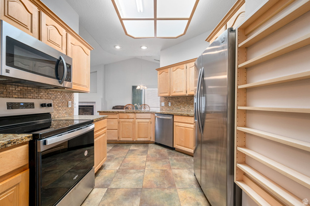 39 North Valley View Drive, Unit 51 St. George, UT 84770 - Photo 13 of 25 Kitchen featuring wood cabinetry, stainless steel appliances, granite countertops, a tiled backsplash, and multi-toned tile flooring
