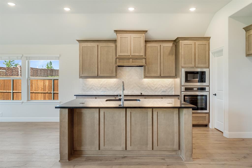 729 Seahawk Street Joshua, TX 76058 - Photo 14 of 40 a kitchen with stainless steel appliances granite countertop a sink and stove top oven