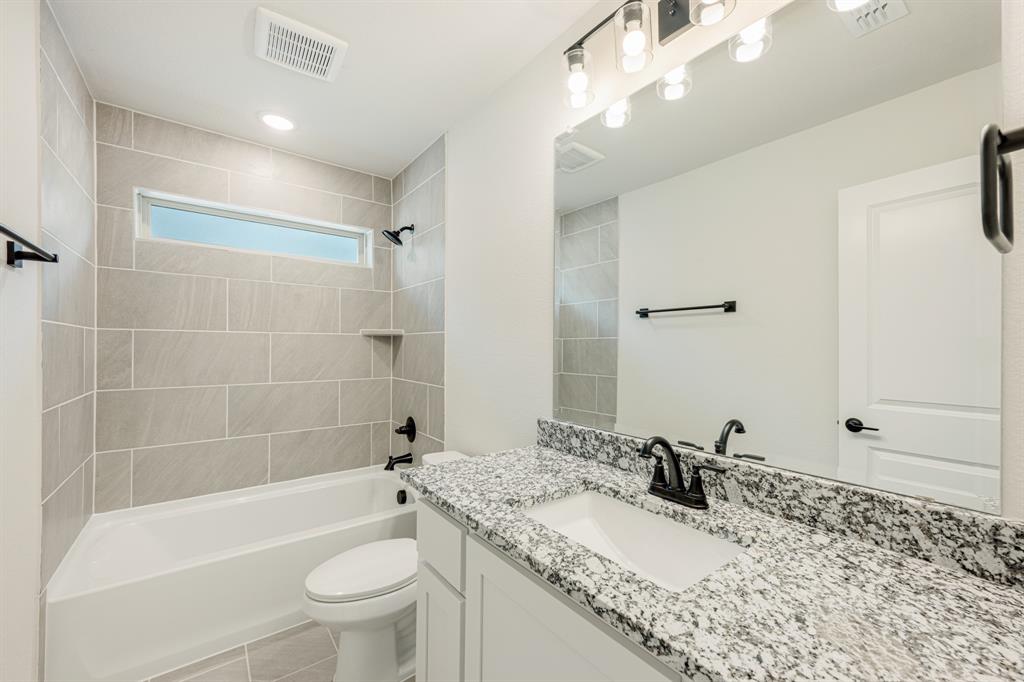 729 Seahawk Street Joshua, TX 76058 - Photo 33 of 40 a bathroom with a granite countertop sink a toilet a mirror a bathtub and shower