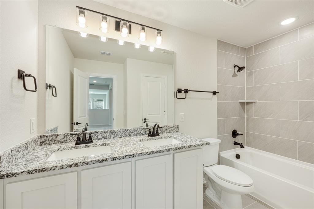 729 Seahawk Street Joshua, TX 76058 - Photo 36 of 40 a bathroom with a granite countertop sink a toilet a mirror and shower