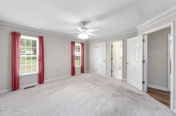 an empty room with chandelier fan and windows