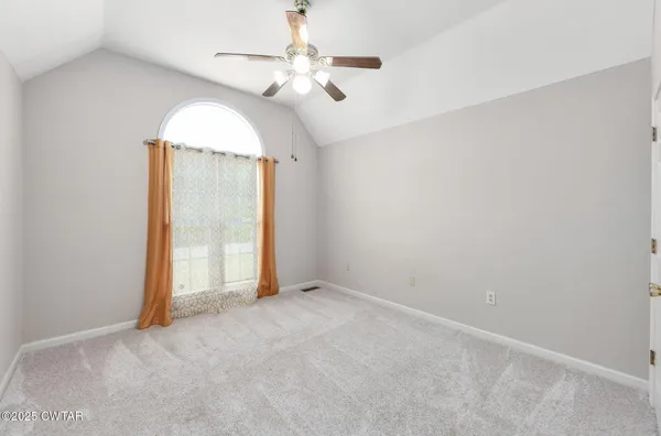 an empty room with a chandelier fan and windows