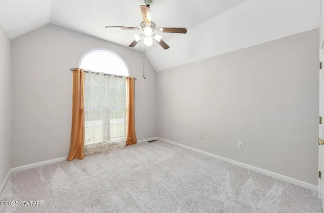 an empty room with a chandelier fan and windows