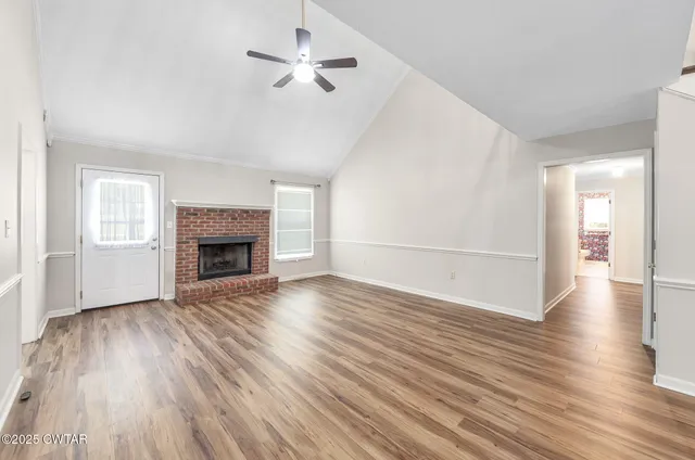 an empty room with wooden floor fireplace and windows