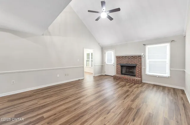 an empty room with wooden floor a fireplace and windows
