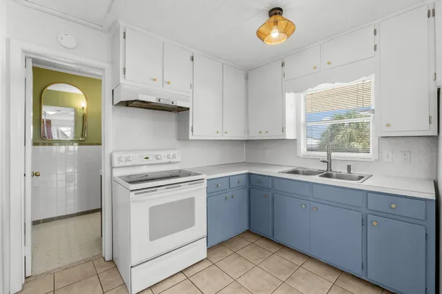 a large white kitchen with a sink dishwasher a refrigerator and cabinets
